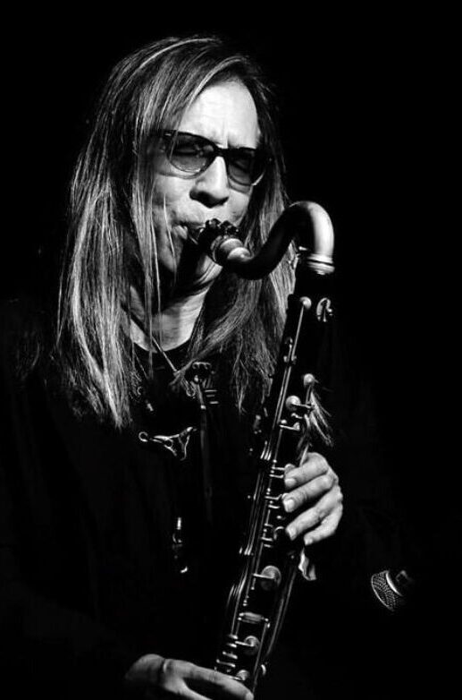 black and white photo of alto saxophonist tracy wannomae playing his sax against a dark black background